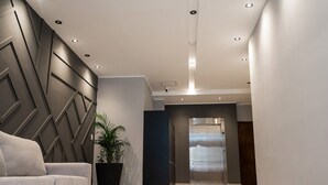 A modern lobby with a sofa, a potted plant, and an elevator. - Triple apartment one block from the Main Sq. (Salta)