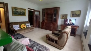 Una sala de estar con un sofá, un sillón reclinable, un aparador y un televisor.