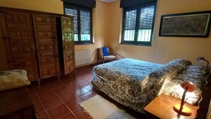 Un dormitorio con cama, una silla, un armario y una ventana con persianas.