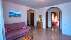 A living room with a sofa, a coffee table, a bookshelf, and a painting on the wall. - Casa Tramonti D Amare - On the Hills of the Amalfi Coast (Tramonti)
