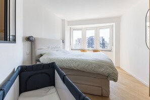 A bedroom with a bed, a small table, and a window with a view of buildings. - 3 bedroom accommodation in Wenduine (Wenduine)