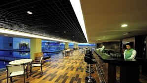 Zona de bar con vistas a la piscina, suelo de madera y mostrador con taburetes.