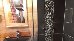 A bathroom with a wooden vanity, a sink, and a shower with mosaic tiles.