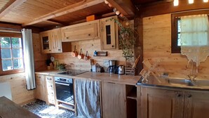 A rustic wooden kitchen with a built-in oven, a sink, and various kitchen utensils.