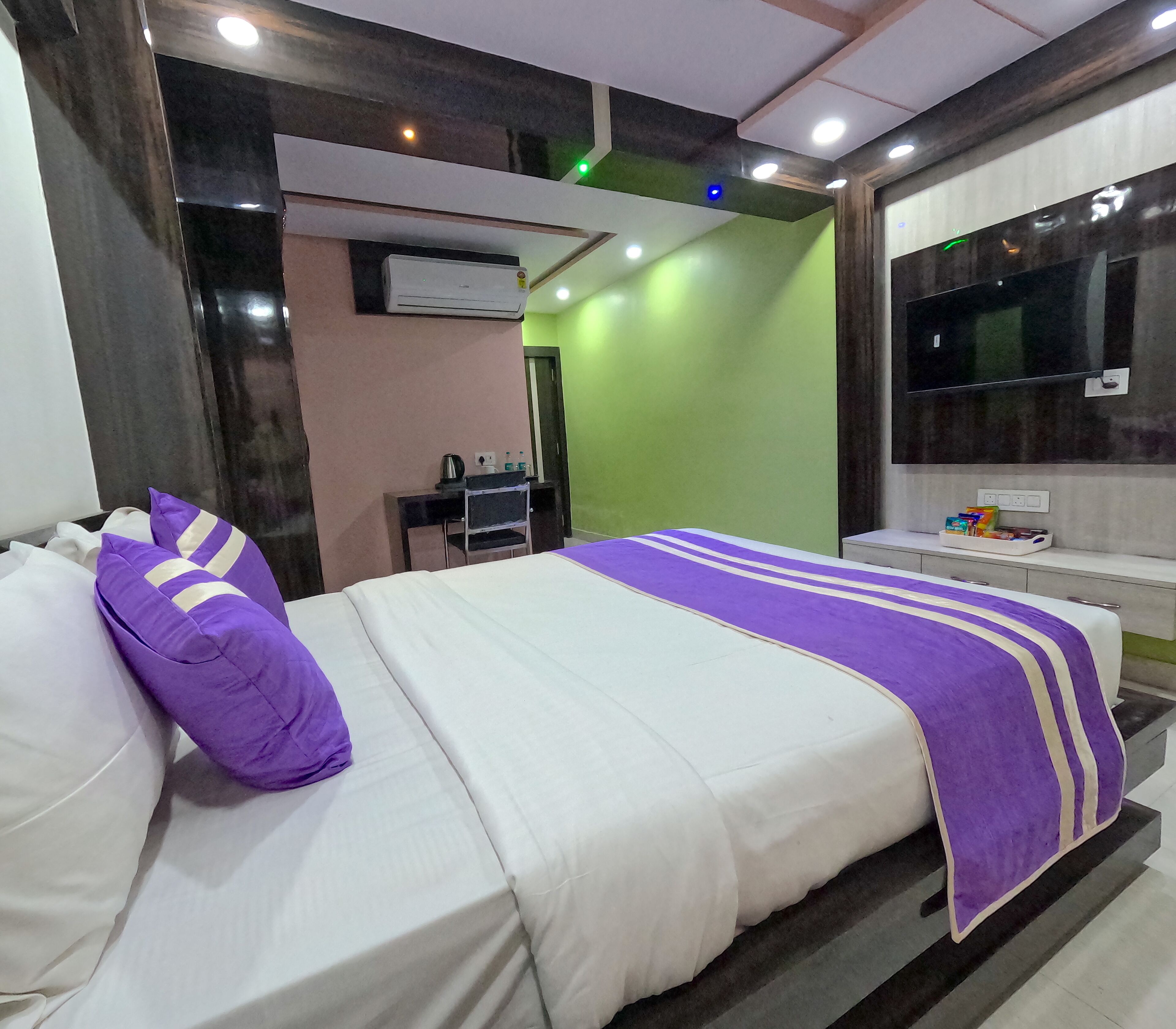 A modern hotel room with a bed, a desk, and a TV.