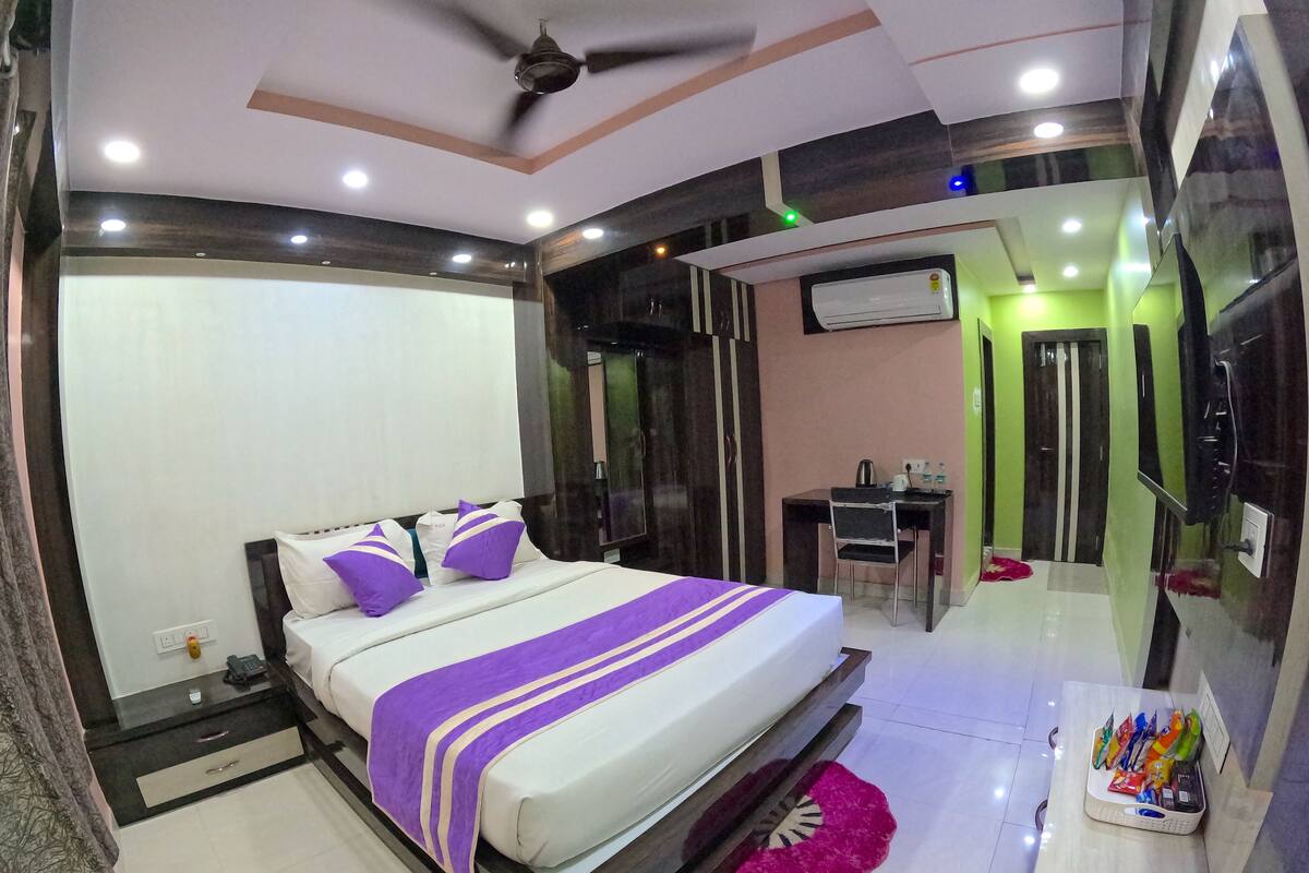 A modern hotel room with a large bed, a desk, and a mirror.