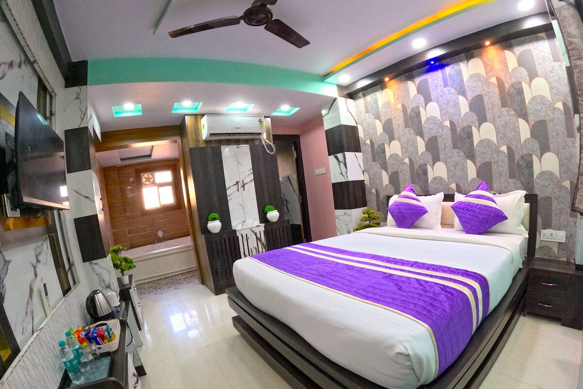 A modern bedroom with a large bed, a ceiling fan, and a built-in TV.