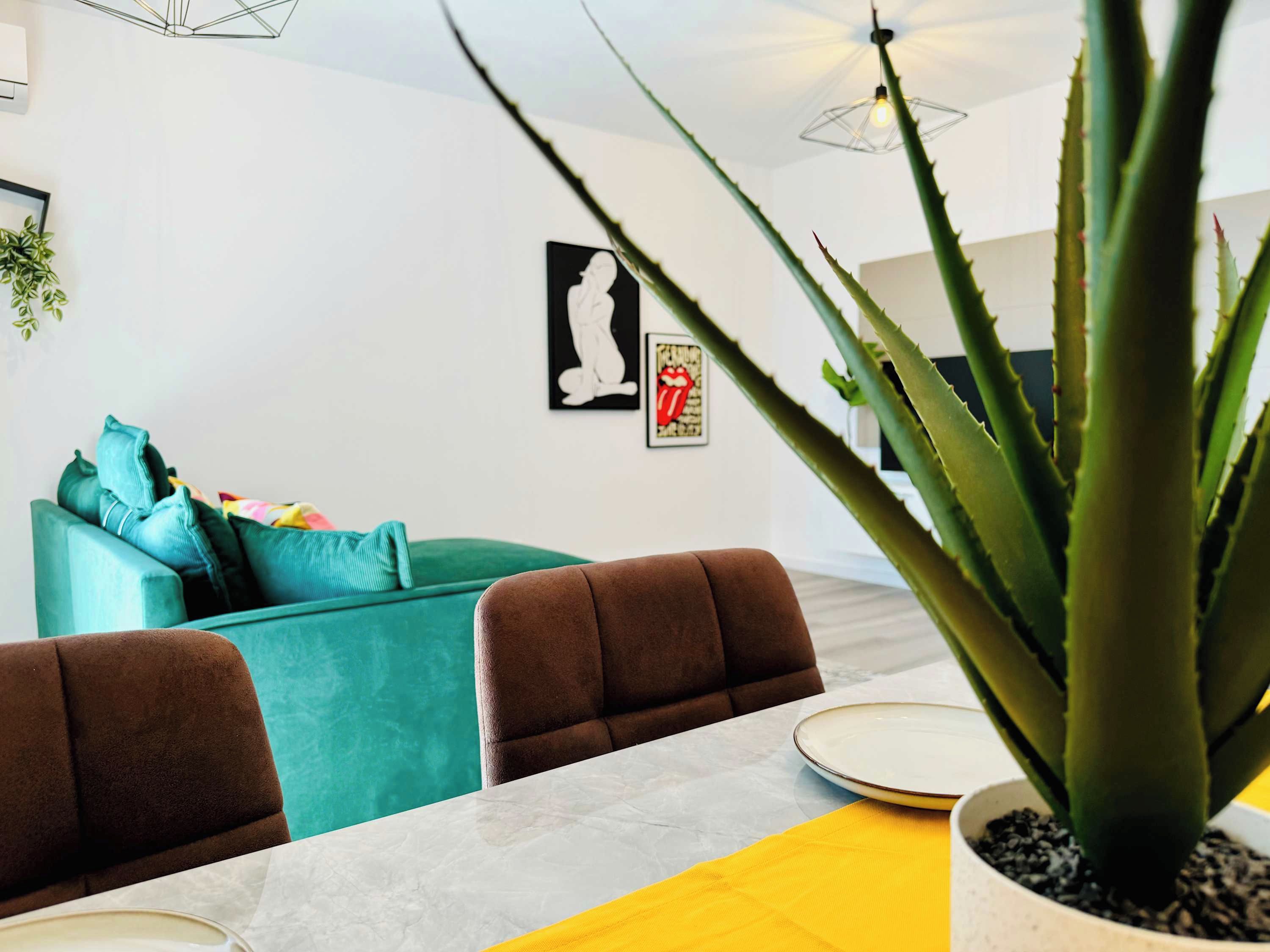 A dining area with a table, chairs, and a large potted plant.