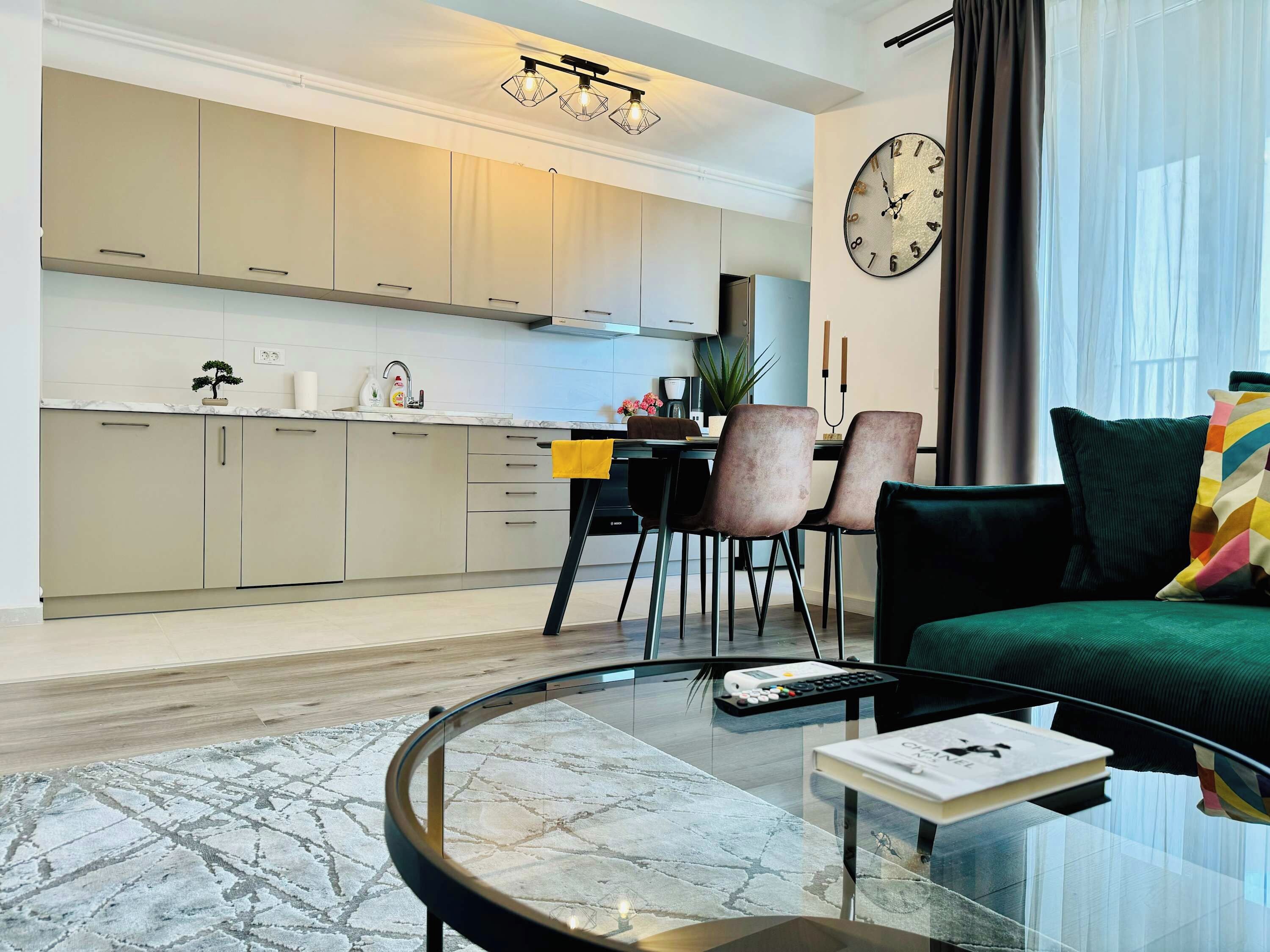 A modern living room with a glass coffee table, a sofa, and a dining area with chairs.