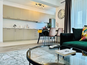 Una sala de estar moderna con una mesa de centro de vidrio, un sofá y un comedor con sillas.