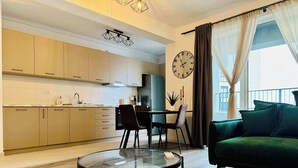 Een moderne keuken met kasten, een eettafel, stoelen en een ronde glazen tafel in de woonruimte.