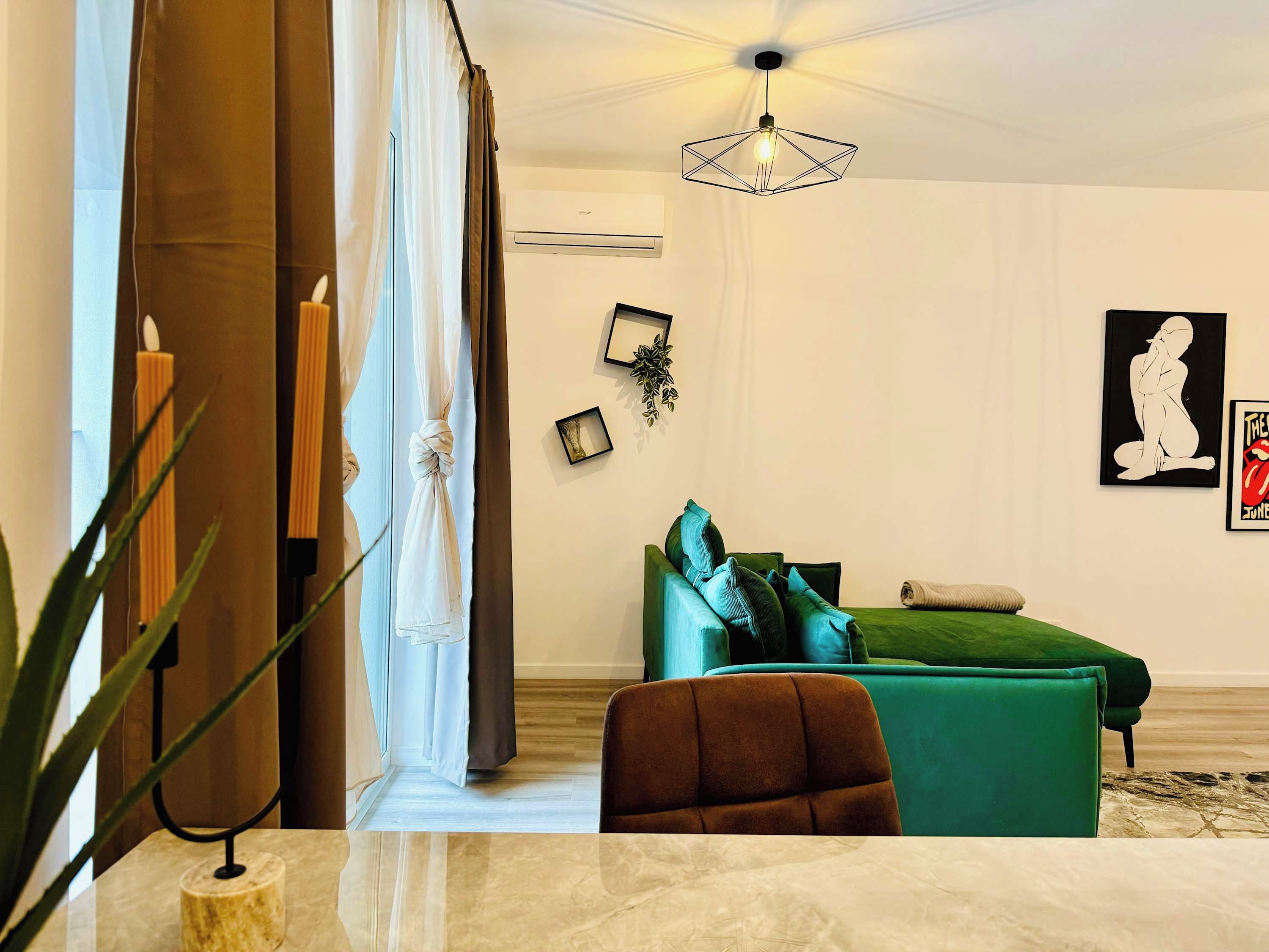 A modern living room with a green sofa, a brown armchair, and a marble coffee table.