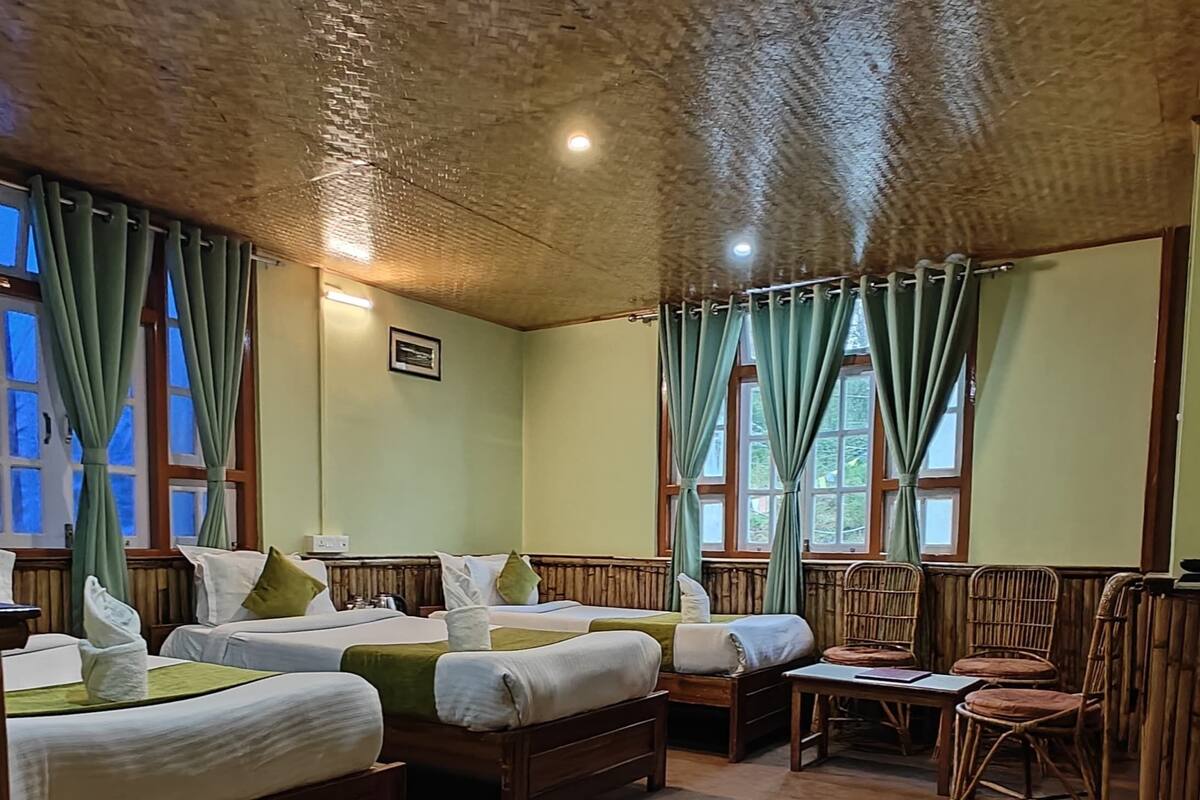 A room with two wooden beds, a small table, wicker chairs, and a carpeted floor.