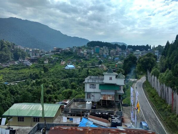 A residential area with houses, a road, and a mountain in the background. - Hotel Ravongla Star (Namchi)