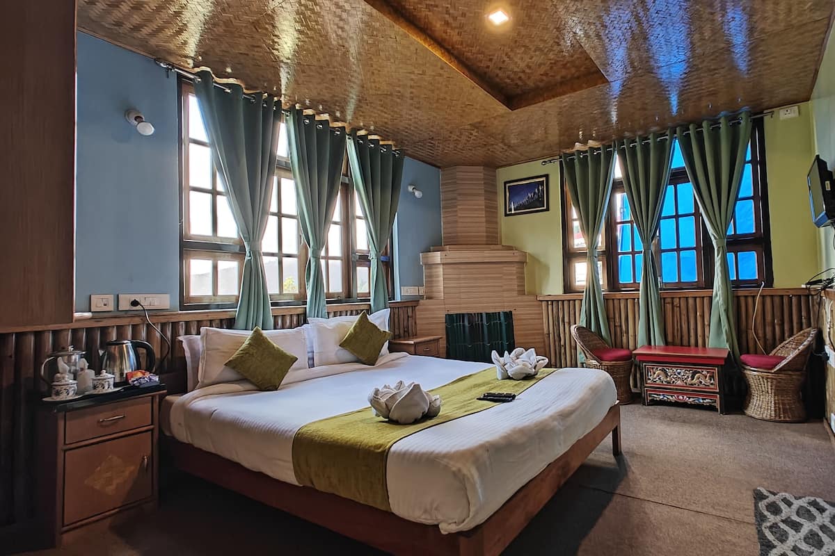 A cozy bedroom with a wooden bed, a nightstand, a chair, and a TV.