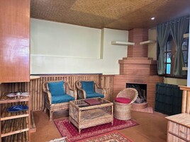 A cozy living area with wicker furniture, a fireplace, and a staircase.