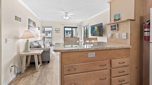 A kitchen with wooden cabinets, a marble countertop, and a ceiling fan. - Ocean Forest Villas D314 - Ocean View! (Myrtle Beach)