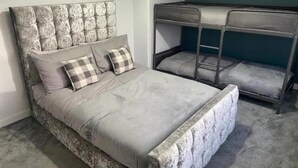 A bedroom with a bed, two pillows, a bunk bed, and a carpeted floor. - Renfrew Apartment Near Glasgow Airport (Renfrew)