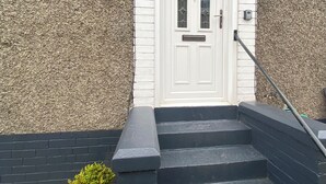 A white door with a small window, a black handrail, and a potted plant beside the steps. - Renfrew Apartment Near Glasgow Airport (Renfrew)