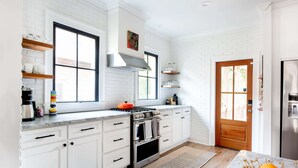 Una cocina con armarios blancos, estufa y refrigerador.