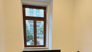 Ein Schlafzimmer mit einem großen Bett, zwei Nachttischen, einem Fenster und Blick auf Gebäude.