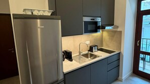 Eine moderne Küche mit dunklen Schränken, einem Edelstahl-Kühlschrank und einem eingebauten Backofen.
