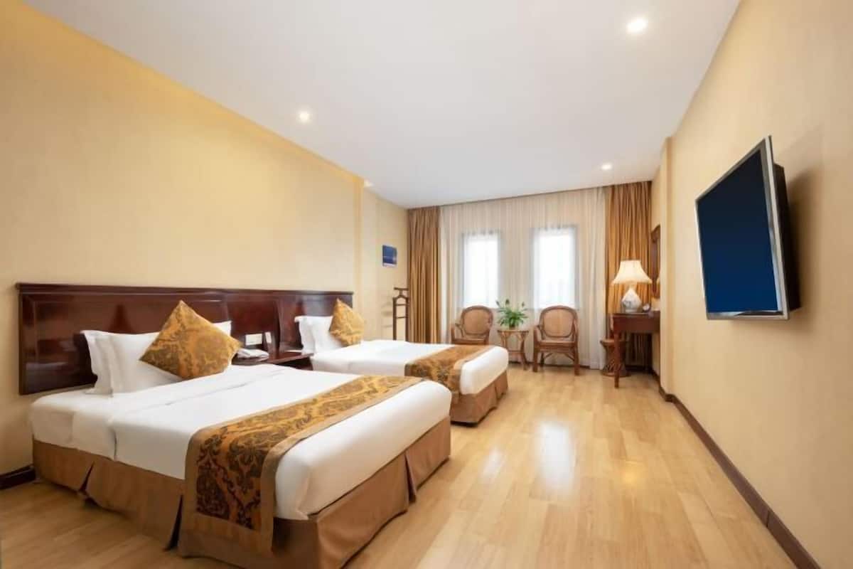 A hotel room with two beds, a TV, a desk, and a chair.