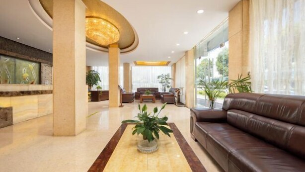 Un hall espacioso con una zona de estar central, ventanas amplias y un moderno candelabro.