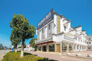 A hotel with a prominent sign, multiple floors, and a clear sky.