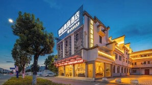 Un hotel de estilo arquitectónico tradicional, con un letrero llamativo y una fachada bien iluminada.
