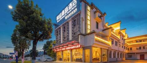 Un hotel de estilo arquitectónico tradicional, con un letrero llamativo y una fachada bien iluminada.