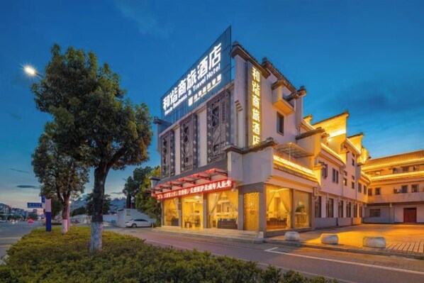 A hotel with a traditional architectural style, featuring a prominent sign and a well-lit facade.