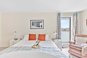 A hotel room with a bed, bedside tables, a window with a view, and a chair.