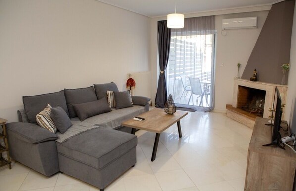 A modern living room with a grey sectional sofa, a wooden coffee table, and a fireplace.