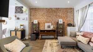 Ein Wohnzimmer mit Backsteinwand, einer Couch, einem Couchtisch und einem Fernseher.
