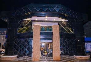 A modern building with a geometric facade and a central entrance with brick pillars. - Joker Hotel and Suites  (Benin City)
