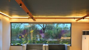 Un interior moderno con un sofá gris, una mesa de centro de madera y un ventanal que ofrece vistas a zonas verdes.