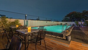 Un área de piscina al aire libre con una mesa y sillas, una piscina pequeña y un borde de piedra.