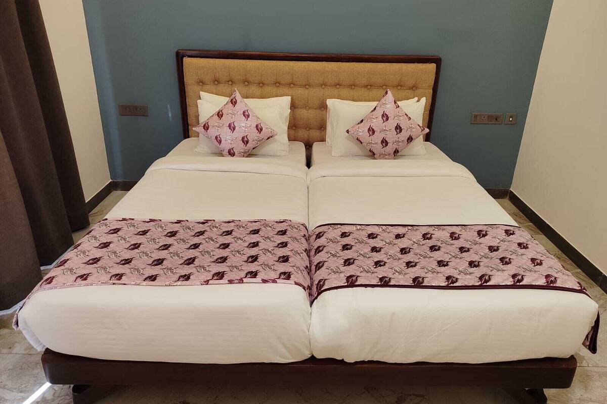 Un lit double avec une tête de lit en bois, deux oreillers à motifs de feuilles et une couvre-lit assortie.