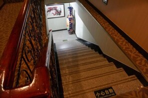 Una escalera con barandilla y un rellano alfombrado.