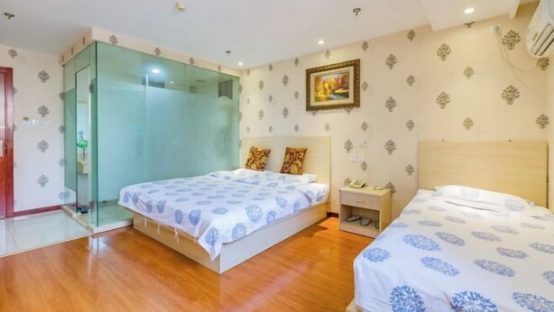 Une chambre avec deux lits, une cabine de douche en verre, une table de chevet avec un téléphone et un papier peint à motifs.