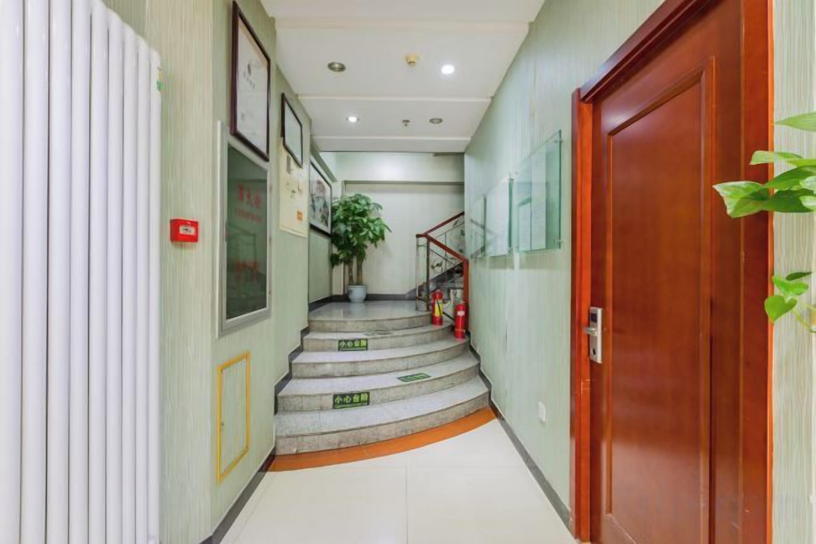 A hallway with a wooden door, a staircase, and a potted plant.