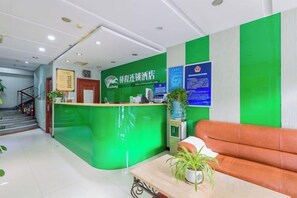 A reception area with a green counter, a brown sofa, and a staircase in the background. - Yucheng Hotel (Beijing Tongzhou Dongzhimen Hospital) (Beijing)