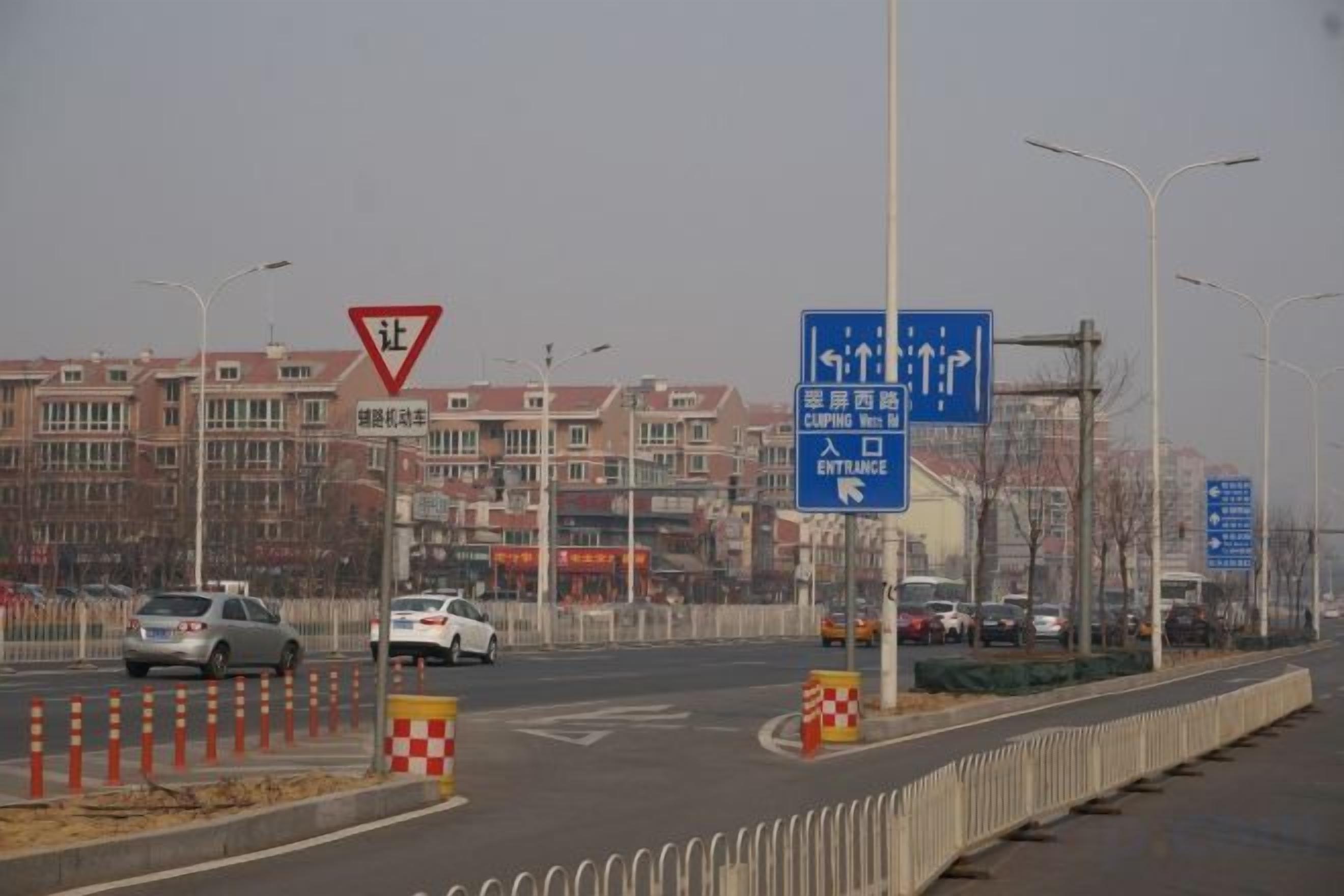 A road with traffic signs and a blue directional sign.