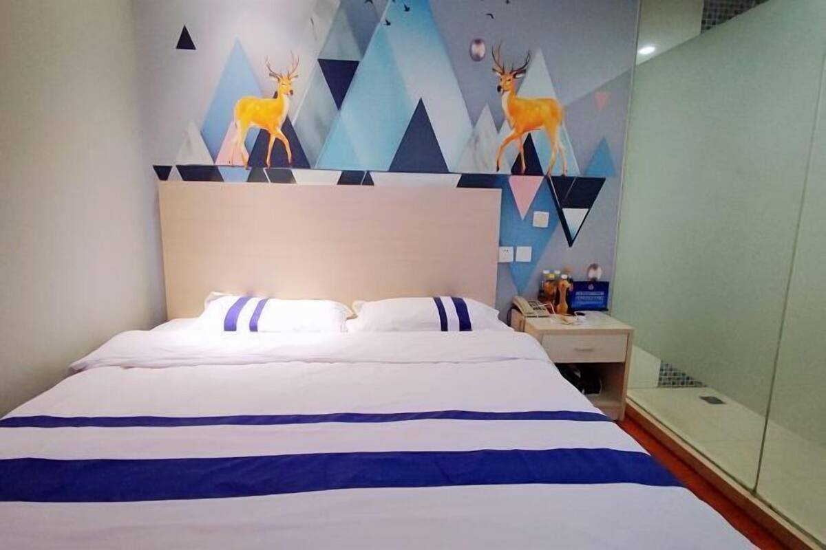 Een hotelkamer met een bed, nachtkastje en een muur met geometrische patronen en dierenillustraties.