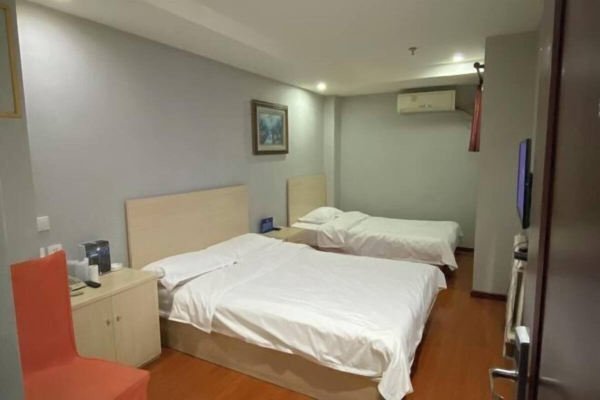 Een hotelkamer met twee bedden, een bureau, een stoel en een schilderij aan de muur.