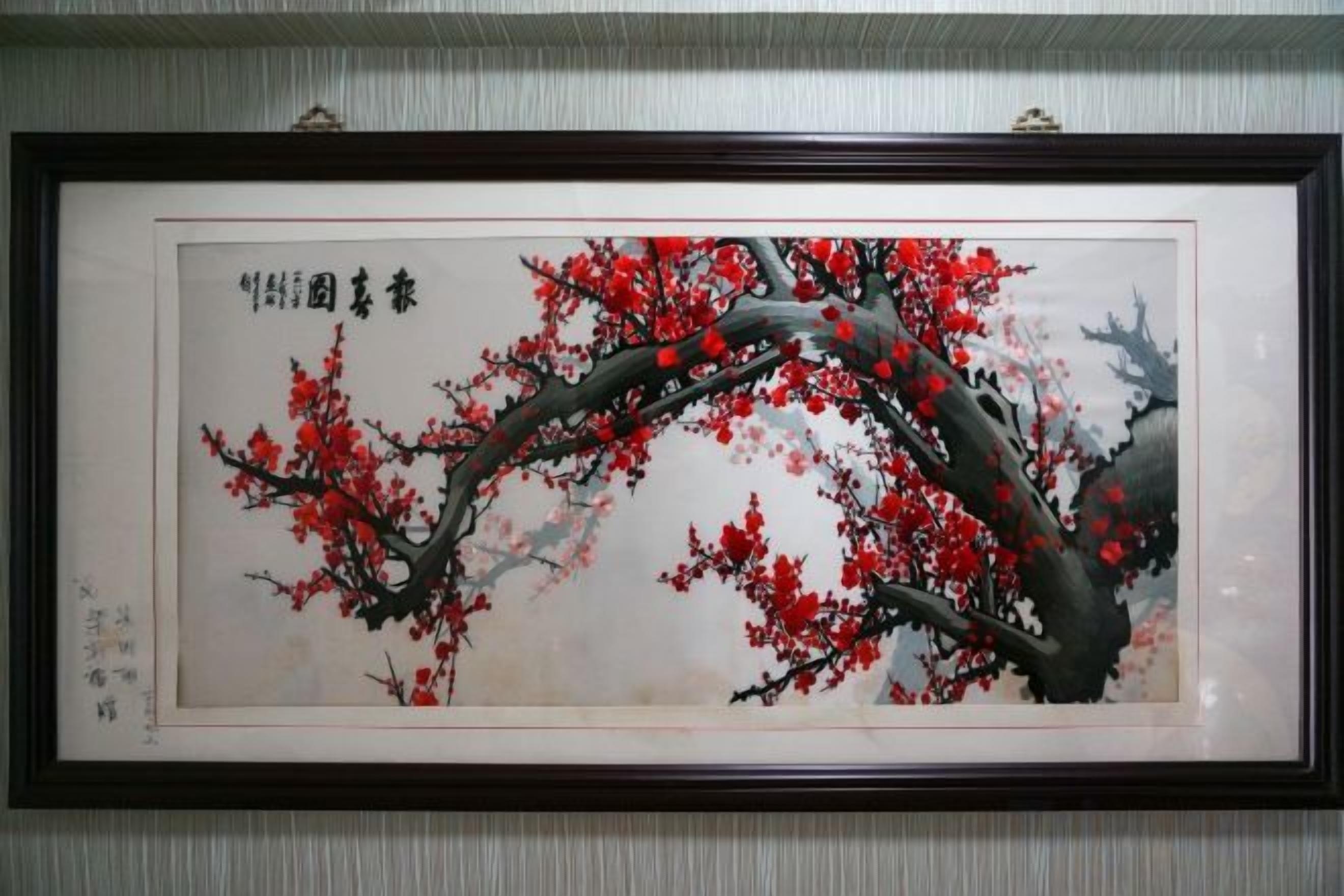 A framed artwork of a tree with red blossoms.