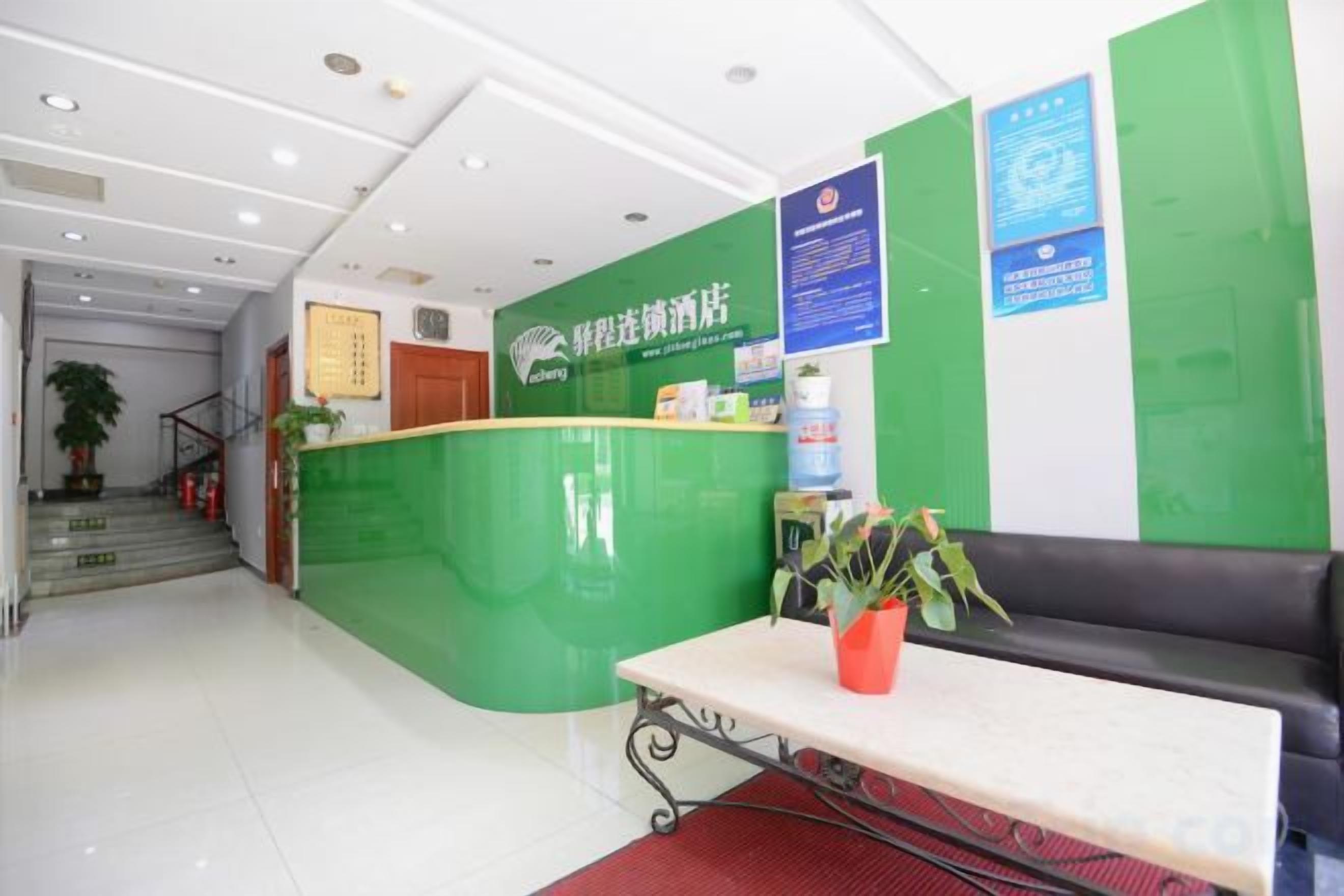 A reception area with a green counter, a reception desk, a seating area, and a staircase in the background.