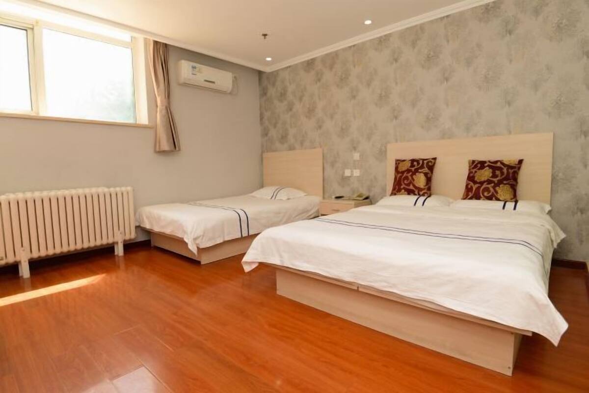 Een slaapkamer met twee bedden, een radiator en een raam.