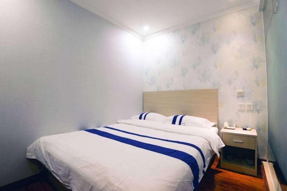 Een slaapkamer met een bed, nachtkastje en wandlamp.